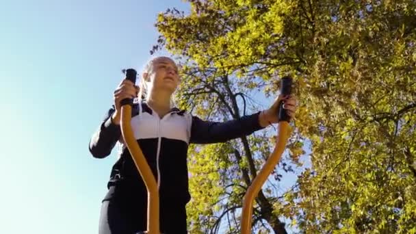 Active fit girl szkolenia na rowerze treningowym pod żółte drzewa na zewnątrz — Wideo stockowe