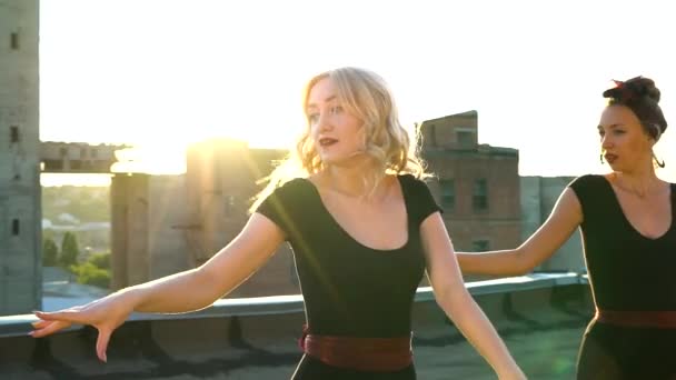 Charming blonde girls dancing on roof of abandoned building at sunset. — Vídeo de stock