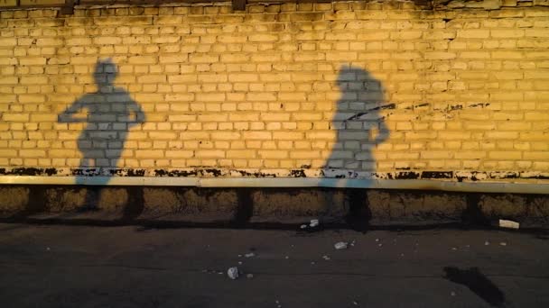 Gün batımında aynı anda tuğla duvara karşı dans eden kızların siluetleri. — Stok video