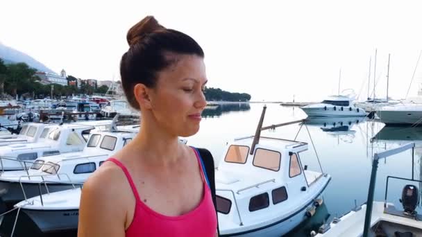 Mujer atlética caminando a lo largo de la playa con veleros en el fondo — Vídeos de Stock