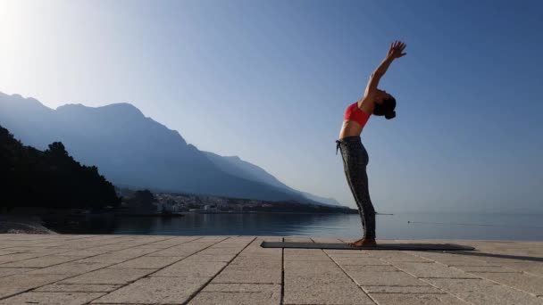 Manzaralı deniz manzarasında yoga yapan esnek bir kız. — Stok video