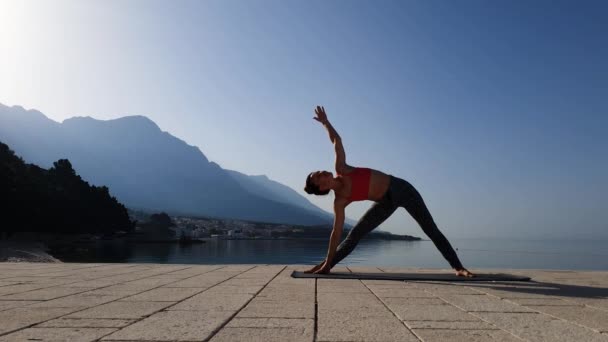 Atleta feminina em pé em poses de ioga em bela paisagem marinha — Vídeo de Stock