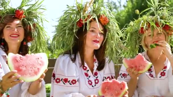 Vrolijke meisjes in bloemencirkels eten watermeloenen buiten in de zomer — Stockvideo