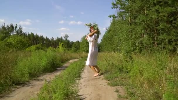 Šťastná bosá dívka v etnickém kostýmu běží na venkovské silnici v létě — Stock video