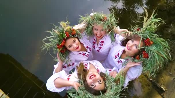 Vier gelukkige meisjes in bloemencirkels en geborduurde jurken poseren in het water — Stockvideo