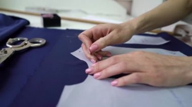 Terzinin elleri atölyedeki kumaşa kağıt desenleri tutturuyor.