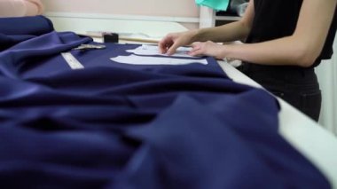 Genç terzi atölyedeki kumaşa kağıt desenleri tutturuyor.