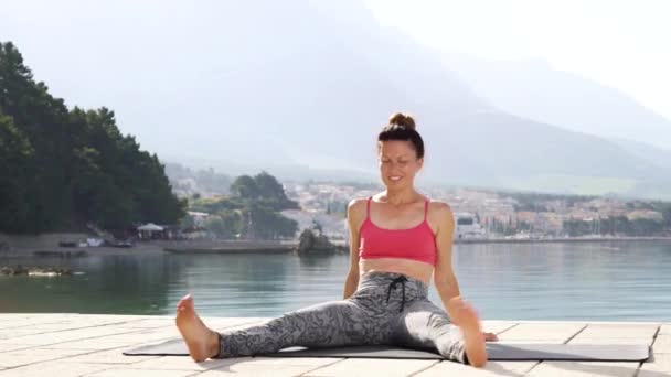 Спортсменка розслабляється після занять з йоги біля моря — стокове відео