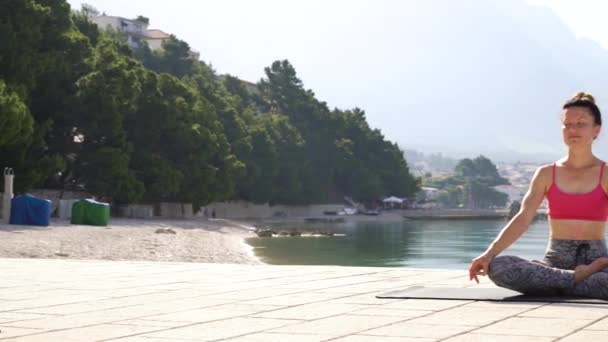 Peaceful woman meditating in lotus pose by the sea — Stock Video
