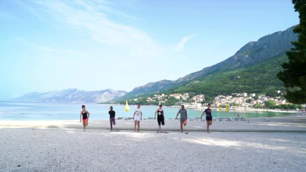 Manzaralı deniz kıyısında yoga dersinde tek ayak üstünde dengede duran mutlu arkadaşlar. — Stok video