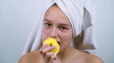 Sivilceli neşeli genç banyo üstüne elma yiyor.