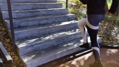 Spor ayakkabılı bir kadın parktaki beton merdivenlerde koşuyor.