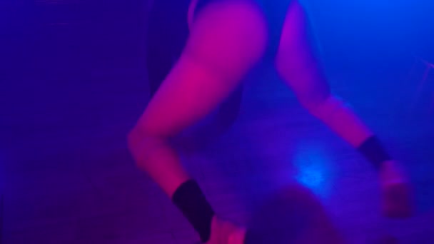 Привлекательная девушка в сексуальном наряде стоит на коленях и тверкает в неоновом свете — стоковое видео
