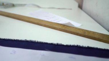 Moda atölyesindeki mavi kumaşa kağıt desenleri tutturan terzi.