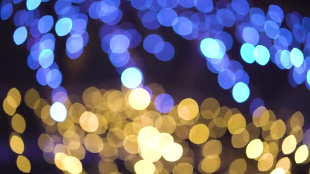 Bokeh cercles bleus et dorés de lumières de fête agitant sur fond noir 