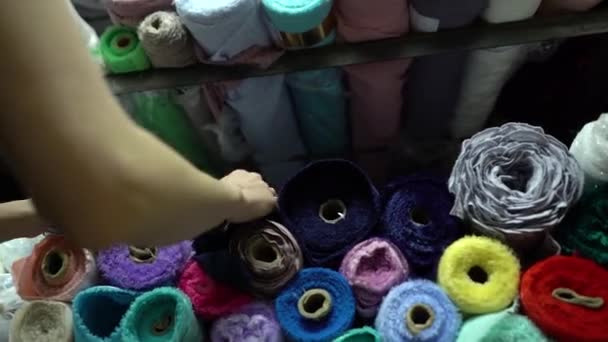 Dressmaker taking blue fabric roll from big pile in fashion atelier — Stock Video