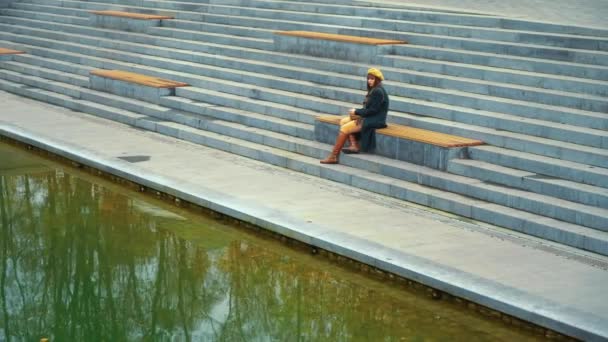 Droevig meisje zit in slechte houding op trappen in openbaar park — Stockvideo
