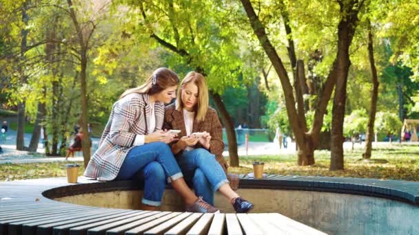 Vrolijke meisjes in hipster outfits met behulp van smartphones in zonnige tuin — Stockvideo