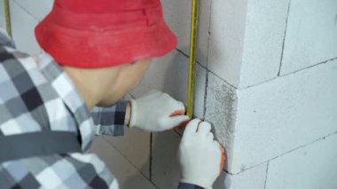 İşteki genç müteahhit montaj klipsleri ve blok duvarına metal korkuluklar takıyor