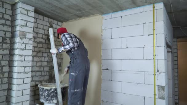 Professioneller Bauarbeiter nivelliert Stuck auf Porenbetonsteinwand — Stockvideo