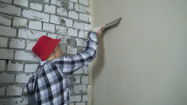 Joven constructor aplanamiento de la pared de yeso en el sitio de construcción — Vídeos de Stock