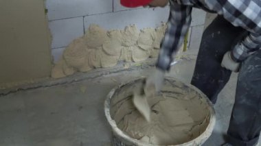 İnşaatçı kovadan sıva alıp blok duvarına asıyor.