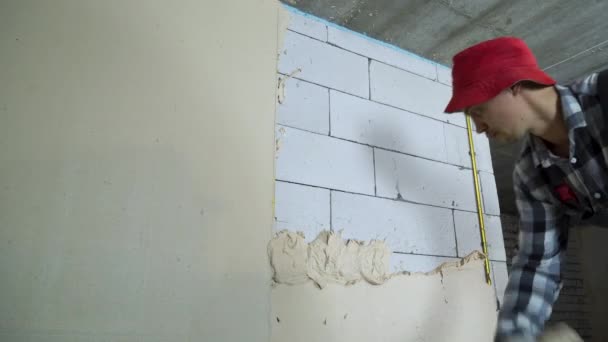 Jovem construtor colocando gesso na parede do bloco — Vídeo de Stock