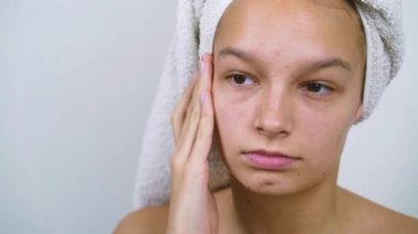 Mutsuz üstsüz kız banyo yaptıktan sonra derisini inceliyor.