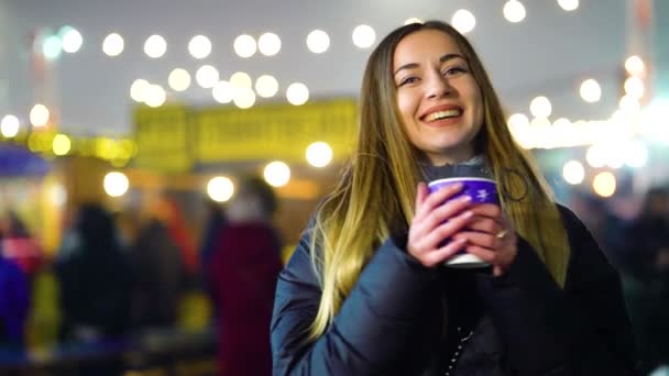 Menina atraente com bebida quente no inverno com iluminação no fundo — Vídeo de Stock