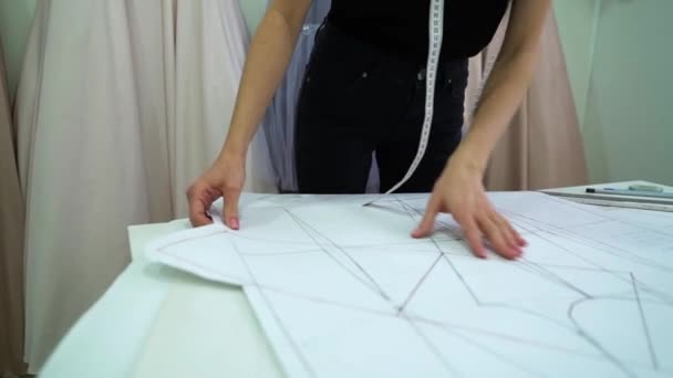 Creativa sarta modello di vestiti in movimento sdraiato sul tavolo in atelier di moda — Video Stock