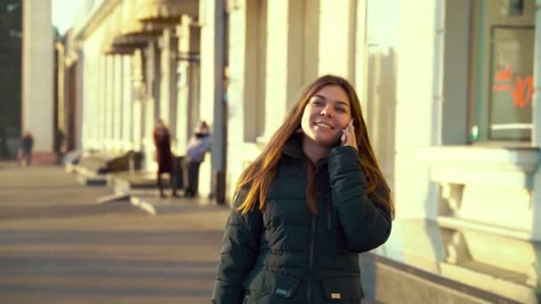 Gelukkig meisje lopen op straat en praten over de telefoon — Stockvideo