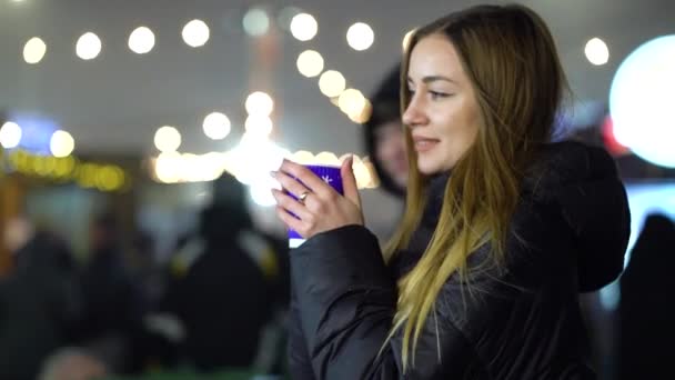 Menina segurando xícara de vinho quente quente mulled no mercado de Natal à noite — Vídeo de Stock