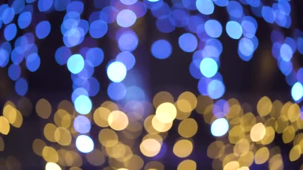 Bokeh lichten van blauwe en gouden bloemenslingers van vakantie decoraties buiten — Stockvideo
