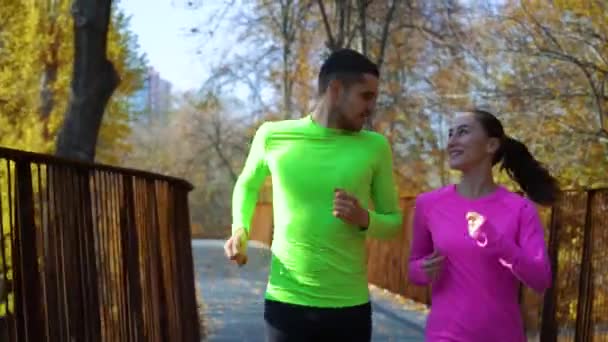 Ochtend joggen door gelukkig jong paar in de herfst park — Stockvideo