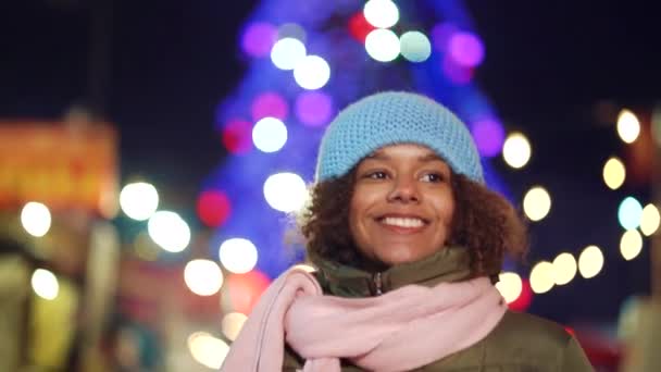 Счастливая чернокожая девушка гуляет по рождественскому базару ночью — стоковое видео