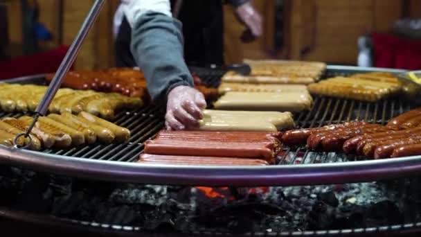 Párky na kovové mřížce nad grilem na dřevěném uhlí na prázdninovém trhu — Stock video