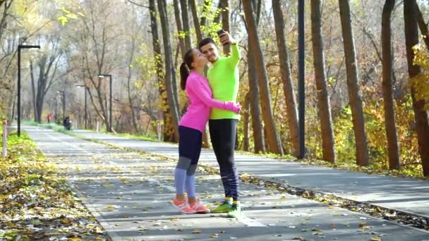Cuplu vesel în dragoste pozând pentru selfie după jogging în parcul de toamnă — Videoclip de stoc