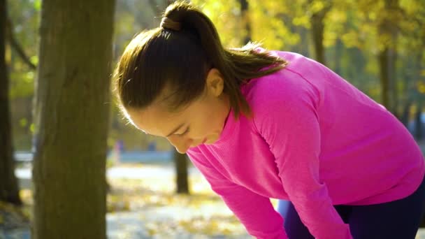 Atletický fit dívka relaxační a dýchání tvrdě po jogging v podzimním parku — Stock video