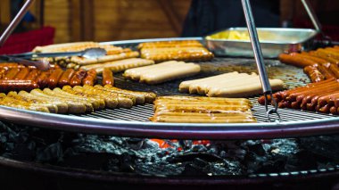 Meat sausages grilling on big grid on market