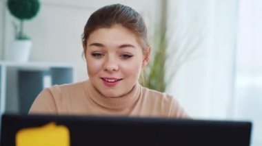 Pretty girl making video call on laptop in office