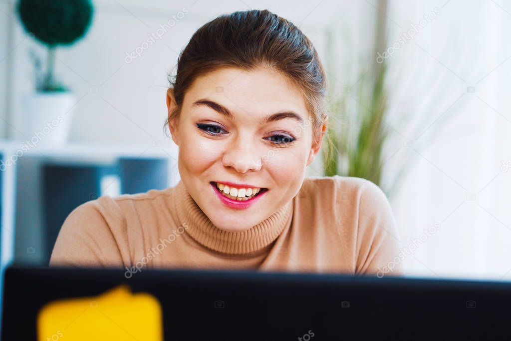 Pretty girl making video call on laptop in office