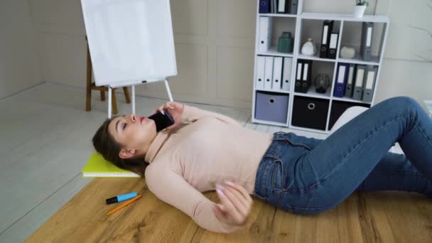 Young business woman lying on table and talking on phone in office — 图库视频影像