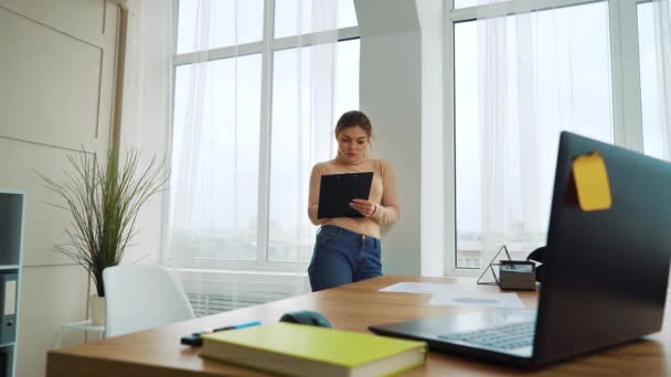 Menina pensativa com prancheta trabalhando no escritório moderno — Vídeo de Stock