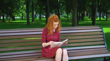 Unhappy girl reading book in park and frowning her brows