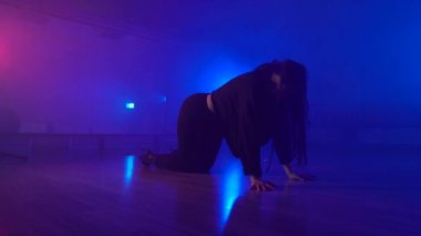Sexual brunette girl dancing in dark studio with artificial fog
