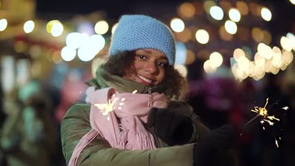 Joyful black girl with sparklers on Christmas holiday market — Stock Video