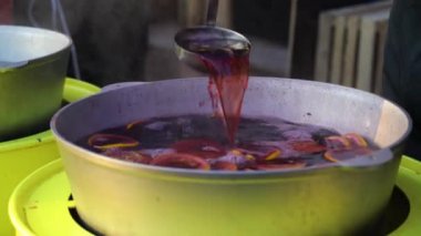 Steamy hot mulled wine scooped with ladle on Christmas market