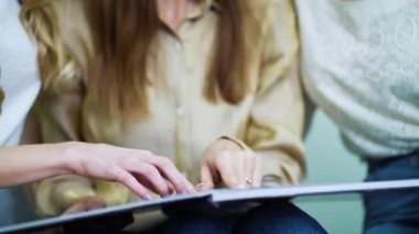 Gelin ve nedimelerin elleri kuafördeki katalogda gelinlik seçiyor.