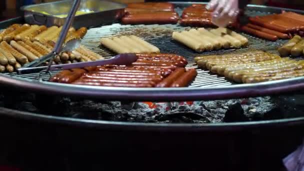 Klobásy a hranolky grilující na velké kovové mřížce na trhu dovolených — Stock video