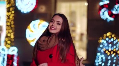 Çekici bir kız Noel ışıklarıyla süslenmiş vitrinlerde yürüyor.